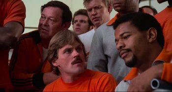 Movie still from “Rollerball” (1975), directed by Norman Jewison – A group of men standing next to each other in orange shirts; Close Up shot, Low angle