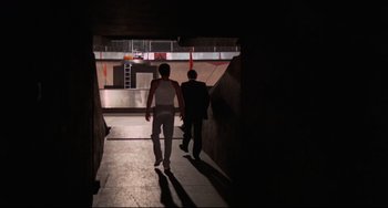 Movie still from “Rollerball” (1975), directed by Norman Jewison – Two people are walking down a dark hallway; Wide shot, Low angle