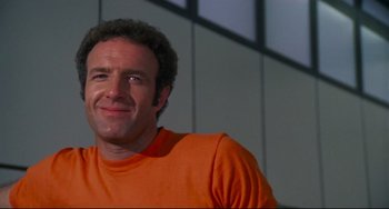 Movie still from “Rollerball” (1975), directed by Norman Jewison – A person wearing an orange t - shirt; Close Up shot, Low angle
