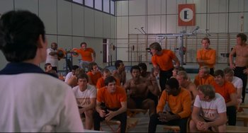 Movie still from “Rollerball” (1975), directed by Norman Jewison – A group of men sitting in a room; Wide shot, Over the shoulder angle