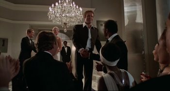 Movie still from “Rollerball” (1975), directed by Norman Jewison – A group of people standing in front of a chandelier; Wide shot, Low angle