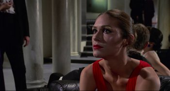Movie still from “Rollerball” (1975), directed by Norman Jewison – A woman in a red dress sitting on a couch; Close Up shot, Low angle