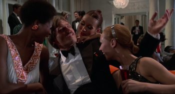 Movie still from “Rollerball” (1975), directed by Norman Jewison – A group of people in formal wear at a party; Medium shot, Low angle
