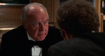 Movie still from “Rollerball” (1975), directed by Norman Jewison – An older man in a tuxedo talking to a younger man; Close Up shot, Over the shoulder angle