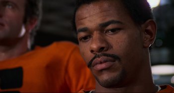 Movie still from “Rollerball” (1975), directed by Norman Jewison – A person wearing an orange shirt; Close Up shot, Low angle