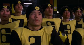 Movie still from “Rollerball” (1975), directed by Norman Jewison – A group of men in yellow shirts and black hats; Close Up shot, Low angle
