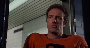 Movie still from “Rollerball” (1975), directed by Norman Jewison – A person wearing an orange t - shirt; Close Up shot, Low angle
