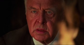 Movie still from “Rollerball” (1975), directed by Norman Jewison – An older man in a suit and tie; Close Up shot, Over the shoulder angle