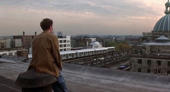 Movie still from “Romeo Is Bleeding” (1993), directed by Peter Medak – A man sitting on the roof of a building looking at a train; Wide shot, Over the shoulder angle