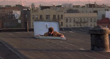 Movie still from “Romeo Is Bleeding” (1993), directed by Peter Medak – A man laying on top of a building on top of a roof; Wide shot, High angle