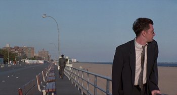 Movie still from “Romeo Is Bleeding” (1993), directed by Peter Medak – A man in a suit standing on a boardwalk; Wide shot, Over the shoulder angle