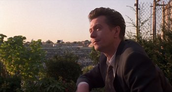 Movie still from “Romeo Is Bleeding” (1993), directed by Peter Medak – A person wearing a suit and tie; Close Up shot, Over the shoulder angle