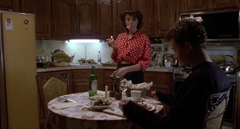 Movie still from “Romeo Is Bleeding” (1993), directed by Peter Medak – A woman standing at a table with a wine glass; Medium shot, High angle