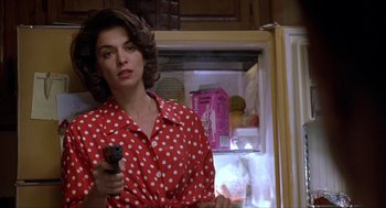 Movie still from “Romeo Is Bleeding” (1993), directed by Peter Medak – A woman holding a gun while standing in front of an open refrigerator; Close Up shot, Low angle