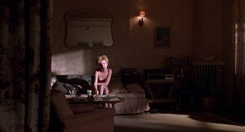 Movie still from “Romeo Is Bleeding” (1993), directed by Peter Medak – A woman sitting on top of a couch in a living room; Wide shot, High angle