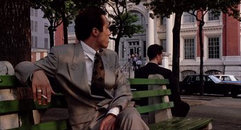 Movie still from “Romeo Is Bleeding” (1993), directed by Peter Medak – A man sitting on a park bench next to another man; Medium shot, Low angle