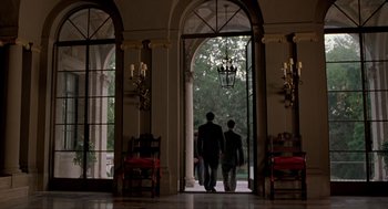 Movie still from “Romeo Is Bleeding” (1993), directed by Peter Medak – Two men are walking through an archway of a building; Wide shot, Low angle