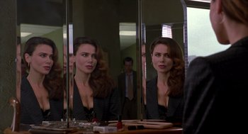 Movie still from “Romeo Is Bleeding” (1993), directed by Peter Medak – A woman looking in the mirror in front of a mirror; Medium shot, Over the shoulder angle