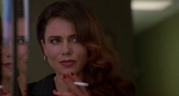 Movie still from “Romeo Is Bleeding” (1993), directed by Peter Medak – A beautiful woman holding a cigarette in her right hand; Close Up shot, Over the shoulder angle