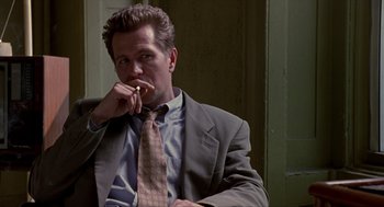 Movie still from “Romeo Is Bleeding” (1993), directed by Peter Medak – A man wearing a suit and tie sitting down; Close Up shot, Low angle