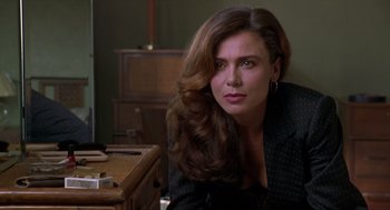 Movie still from “Romeo Is Bleeding” (1993), directed by Peter Medak – A woman sitting at a table in front of a desk; Close Up shot, Over the shoulder angle