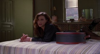 Movie still from “Romeo Is Bleeding” (1993), directed by Peter Medak – A woman sitting on top of a bed next to a table; Medium shot, Over the shoulder angle