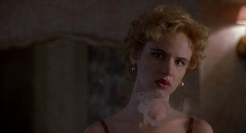Movie still from “Romeo Is Bleeding” (1993), directed by Peter Medak – A woman with blonde curly hair and red lipstick; Close Up shot, Over the shoulder angle