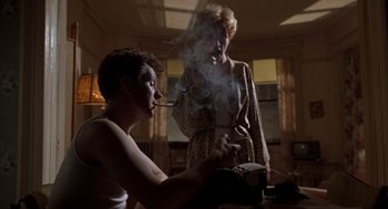 Movie still from “Romeo Is Bleeding” (1993), directed by Peter Medak – A man smoking a cigarette next to a woman; Medium shot, Low angle