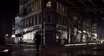 Movie still from “Romeo Is Bleeding” (1993), directed by Peter Medak – A person walking down a street at night; Extreme Wide shot, Low angle