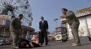 Movie still from “Romeo Is Bleeding” (1993), directed by Peter Medak – A group of men standing around a man laying on the ground; Wide shot, Low angle