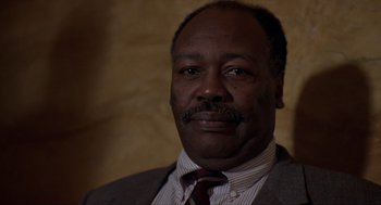 Movie still from “Romeo Is Bleeding” (1993), directed by Peter Medak – A person wearing a suit and tie; Close Up shot, Low angle