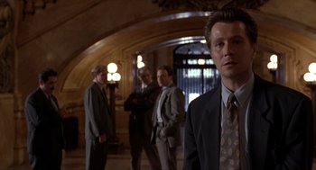 Movie still from “Romeo Is Bleeding” (1993), directed by Peter Medak – A group of men in suits and ties standing in a hallway; Medium shot, Low angle