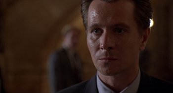 Movie still from “Romeo Is Bleeding” (1993), directed by Peter Medak – A person wearing a suit and tie; Close Up shot, Over the shoulder angle