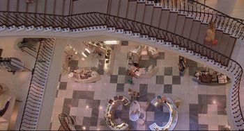 Movie still from “Romy and Michele's High School Reunion” (1997), directed by David Mirkin – An overhead view of a building with a spiral staircase; Extreme Wide shot, Overhead angle