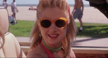 Movie still from “Romy and Michele's High School Reunion” (1997), directed by David Mirkin – A woman with blonde hair wearing sunglasses and a necklace; Close Up shot, Low angle
