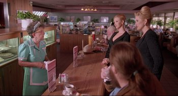 Movie still from “Romy and Michele's High School Reunion” (1997), directed by David Mirkin – A group of people sitting at a counter in a restaurant; Medium shot, Over the shoulder angle