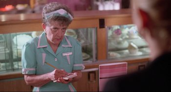 Movie still from “Romy and Michele's High School Reunion” (1997), directed by David Mirkin – An older woman writing on a piece of paper; Close Up shot, Over the shoulder angle