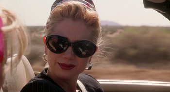 Movie still from “Romy and Michele's High School Reunion” (1997), directed by David Mirkin – A woman wearing sunglasses and a hat; Close Up shot, Over the shoulder angle