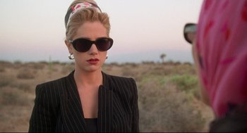 Movie still from “Romy and Michele's High School Reunion” (1997), directed by David Mirkin – A woman wearing sunglasses and a black jacket; Close Up shot, Over the shoulder angle