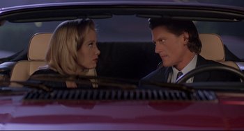 Movie still from “Romy and Michele's High School Reunion” (1997), directed by David Mirkin – A man and a woman sitting in the back seat of a car; Close Up shot, Low angle
