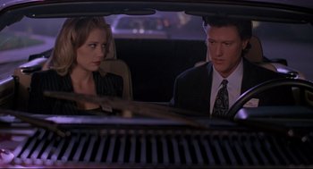 Movie still from “Romy and Michele's High School Reunion” (1997), directed by David Mirkin – A man and a woman sitting in the back of a car; Medium shot, Over the shoulder angle