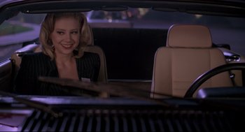 Movie still from “Romy and Michele's High School Reunion” (1997), directed by David Mirkin – A woman sitting in the back seat of a car; Medium shot, Over the shoulder angle