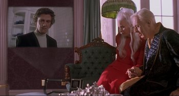 Movie still from “Romy and Michele's High School Reunion” (1997), directed by David Mirkin – Two women sitting in a chair in front of a television; Medium shot, Over the shoulder angle