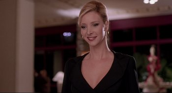 Movie still from “Romy and Michele's High School Reunion” (1997), directed by David Mirkin – A woman in a black dress smiling for the camera; Close Up shot, Low angle