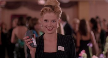 Movie still from “Romy and Michele's High School Reunion” (1997), directed by David Mirkin – A woman holding a cell phone in her hand; Medium shot, Low angle