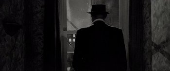 Movie still from “'Round Midnight” (1986), directed by Bertrand Tavernier – A black and white photo of a man in a suit and a hat; Medium shot, Low angle
