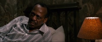 Movie still from “'Round Midnight” (1986), directed by Bertrand Tavernier – An older man sitting in a chair in a room; Close Up shot, High angle