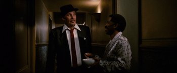 Movie still from “'Round Midnight” (1986), directed by Bertrand Tavernier – A man in a suit and tie and a man in a hat and tie; Medium shot, Low angle