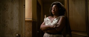 Movie still from “'Round Midnight” (1986), directed by Bertrand Tavernier – A woman standing with her arms crossed in front of a wall; Close Up shot, Low angle