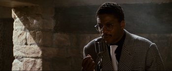 Movie still from “'Round Midnight” (1986), directed by Bertrand Tavernier – A man in a suit and tie holding a microphone; Close Up shot, Low angle